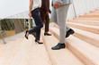 © Mangostar - Businesspeople walking upstairs and downstairs. Legs and feet of business man and women wearing formal trousers and shoes. Business area concept