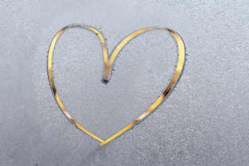 One beautiful bright yellow heart painted by finger on a frozen blue texture on a glass