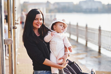 Wall Mural - Mother with pram in casual clothes with her child is in the park