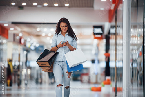 Fotografía Brunette woman in the supermarket with many of packages and phone in hands have