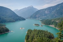 High Angle Shot Of The Diablo Lake In The Middle Of Forested Mountains Under A Blue Sky