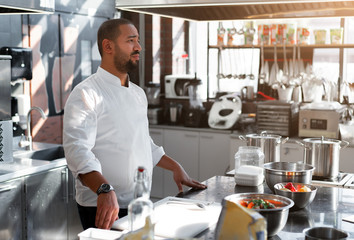 Wall Mural - The chef conducts a master class in cooking. On the background is kitchen utensils, on the table in front of him vegetables in bowls