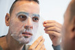 © nito - man applying a facial mask to himself.