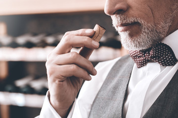 Wall Mural - Sommelier Concept. Senior man standing smelling wine cork close-up