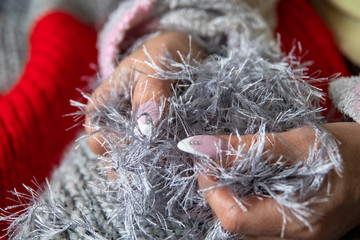 Women with manicured nails knitting with red and silver wool