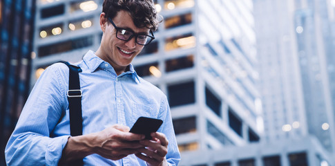 Cheerful man browsing smartphone on street