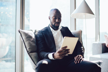 Wall Mural - Serious black businessman using tablet