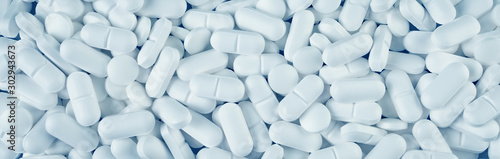 Photographie White pills spilled on blue wooden background
