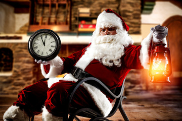 Wall Mural - Red old Santa Claus in rocking chair.Fireplace in home interior.Copy space.Free space for your decoration.Dark mood photo of home interior.Xmas time and cold december night.