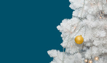 Beautiful White Christmas Tree Decorated With Golden Ball, Garlands And Silver Beads On Blue Background With Copy Space.
