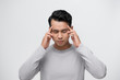 © makistock - Young Asian man having a headache. Concept of stress and overworking. An isolated portrait