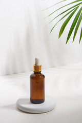 Wall Mural - Serum or essential oil bottle isolated on with background with green leaves. Beauty product concept.