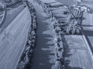 Wall Mural - Aerial view of river Arno between cultivated fields