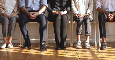 Poster - Professional unemployed business people sit on chairs, legs closeup view