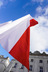 Polish red and white flags in the Old town in front of the building on a Sunny day.May 1, November 11, flag, independence or labor Day. Public holiday in Poland. decoration of the city with flags.