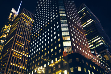 Evening view of skyscraper shining with lights of windows in offices and corporate headquarters in business center,modern constructed building exterior at night with luxury apartment for rent .