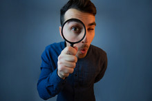 Curious Young Man With Magnifying Glass Isolated On Grey Background.
