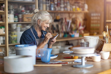 Wall Mural - Mature craftswoman painting a plate made of clay in art studio