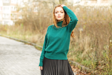 beautiful red-haired woman in a pleated skirt and a green sweater. fashion and style concept, lifest