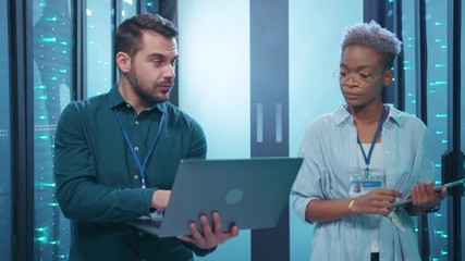 Wall Mural - data center male and female server technicians cooperating in server rack room inspecting system and