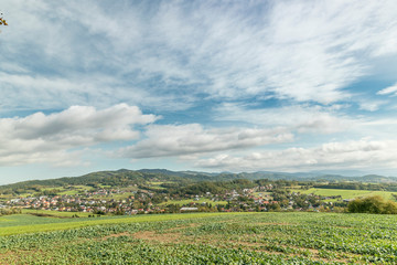 Moving clouds in two directions, above the village of the Krhova Beskydy Czech republic looking at horizon around with visible hills and mountains during sunny days and field for crop