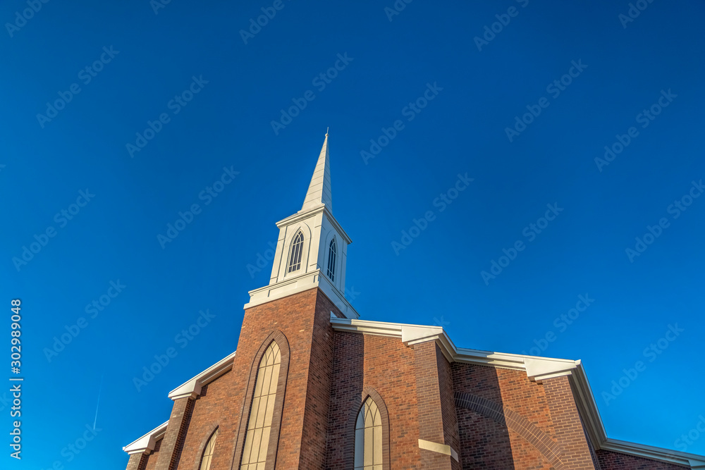 Church with classic red brick exterior wall and white steeple against blue sky - obrazy, fototapety, plakaty 