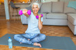 © Dragana Gordic - Senior woman doing fitness exercices in front of tv. Portrait of senior woman lifting dumbbells. Happy senior woman making fitness training with dumbbells