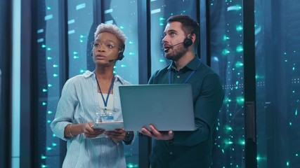 Wall Mural - multi-ethnic couple of server engineers inspecting supercomputer providing webhosting cloud computin