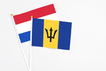 Barbados and Paraguay stick flags on white background. High quality fabric, miniature national flag. Peaceful global concept.White floor for copy space.