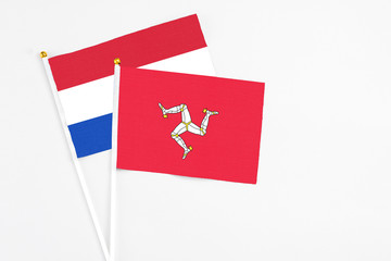 Isle Of Man and Paraguay stick flags on white background. High quality fabric, miniature national flag. Peaceful global concept.White floor for copy space.