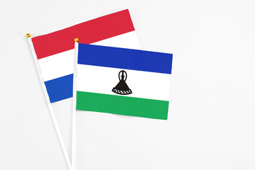 Lesotho and Paraguay stick flags on white background. High quality fabric, miniature national flag. Peaceful global concept.White floor for copy space.