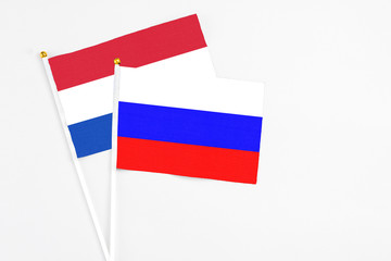 Russia and Paraguay stick flags on white background. High quality fabric, miniature national flag. Peaceful global concept.White floor for copy space.