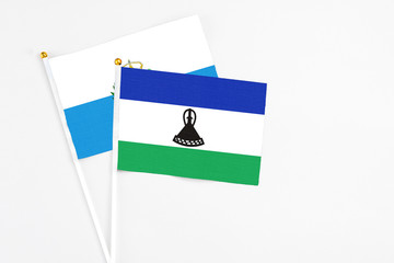 Lesotho and San Marino stick flags on white background. High quality fabric, miniature national flag. Peaceful global concept.White floor for copy space.