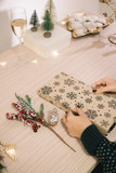 Fototapeta Lawenda - Wrapping Christmas presents on wooden table with trees