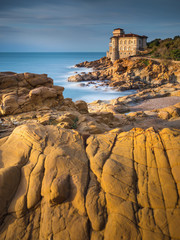 Wall Mural - golden stones on the sea coast and view to old castle in Livorno in Tuscany in Italy