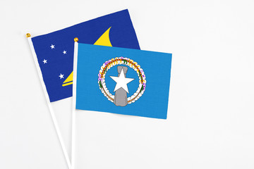 Northern Mariana Islands and Tokelau stick flags on white background. High quality fabric, miniature national flag. Peaceful global concept.White floor for copy space.