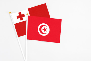 Poster - Tunisia and Tonga stick flags on white background. High quality fabric, miniature national flag. Peaceful global concept.White floor for copy space.