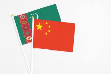 China and Turkmenistan stick flags on white background. High quality fabric, miniature national flag. Peaceful global concept.White floor for copy space.