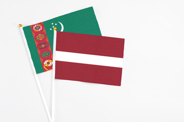 Latvia and Turkmenistan stick flags on white background. High quality fabric, miniature national flag. Peaceful global concept.White floor for copy space.