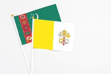 Vatican City and Turkmenistan stick flags on white background. High quality fabric, miniature national flag. Peaceful global concept.White floor for copy space.