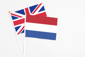 Wall Mural - Netherlands and United Kingdom stick flags on white background. High quality fabric, miniature national flag. Peaceful global concept.White floor for copy space.