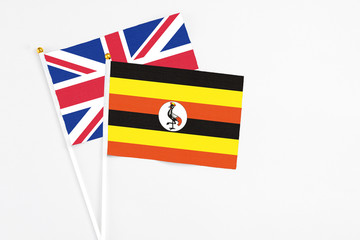 Wall Mural - Uganda and United Kingdom stick flags on white background. High quality fabric, miniature national flag. Peaceful global concept.White floor for copy space.