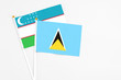 © sezerozger - Saint Lucia and Uzbekistan stick flags on white background. High quality fabric, miniature national flag. Peaceful global concept.White floor for copy space.