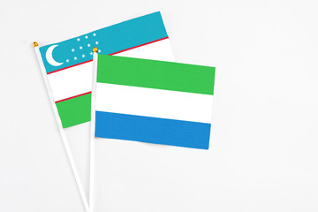 Sierra Leone and Uzbekistan stick flags on white background. High quality fabric, miniature national flag. Peaceful global concept.White floor for copy space.