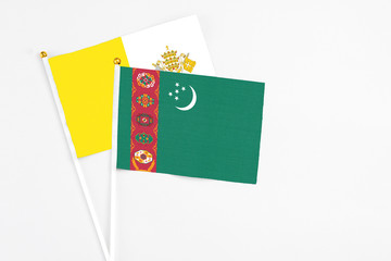 Turkmenistan and Vatican City stick flags on white background. High quality fabric, miniature national flag. Peaceful global concept.White floor for copy space.