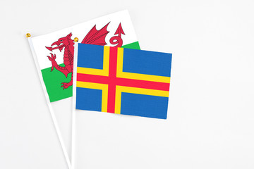 Aland Islands and Wales stick flags on white background. High quality fabric, miniature national flag. Peaceful global concept.White floor for copy space.