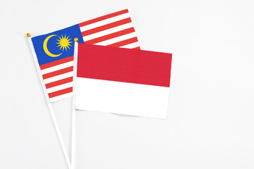 Wall Mural - Indonesia and Malaysia stick flags on white background. High quality fabric, miniature national flag. Peaceful global concept.White floor for copy space.