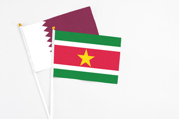 Wall Mural - Suriname and Qatar stick flags on white background. High quality fabric, miniature national flag. Peaceful global concept.White floor for copy space.