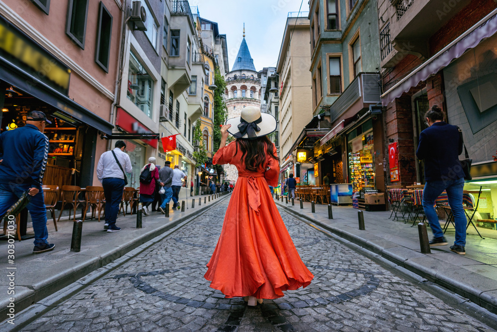 Woman standing at Galata tower in Istanbul, Turkey. - obrazy, fototapety, plakaty 