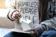 © torsakh - a old man is homeless or beggar sitting or sleeping beside street with cup for request some coin from kindness man and text please help